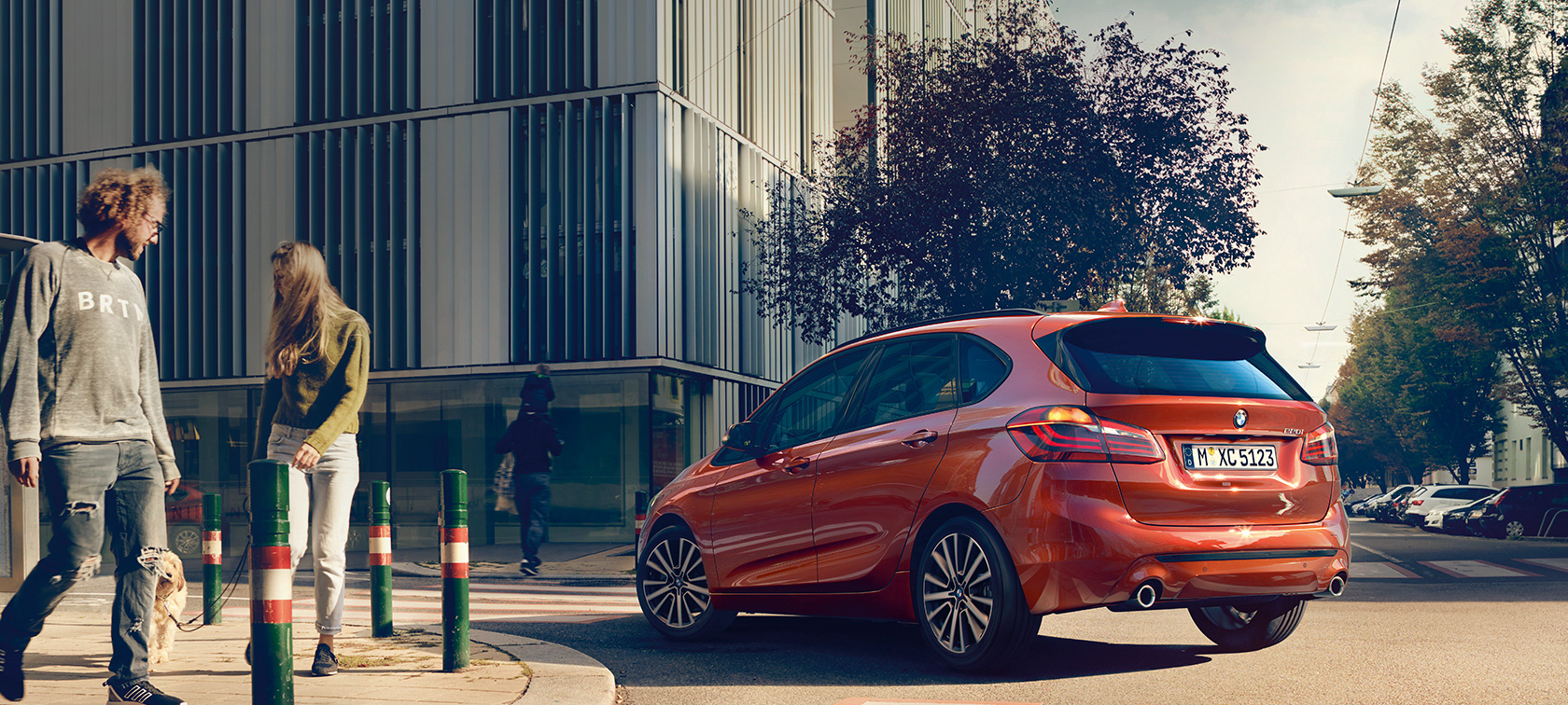 Three-quarter rear view BMW 2 Series Active Tourer 220i BMW 2 Series Active Tourer 220i F45 Facelift 2018 Sunset Orange metallic three-quarter rear view driving on the road