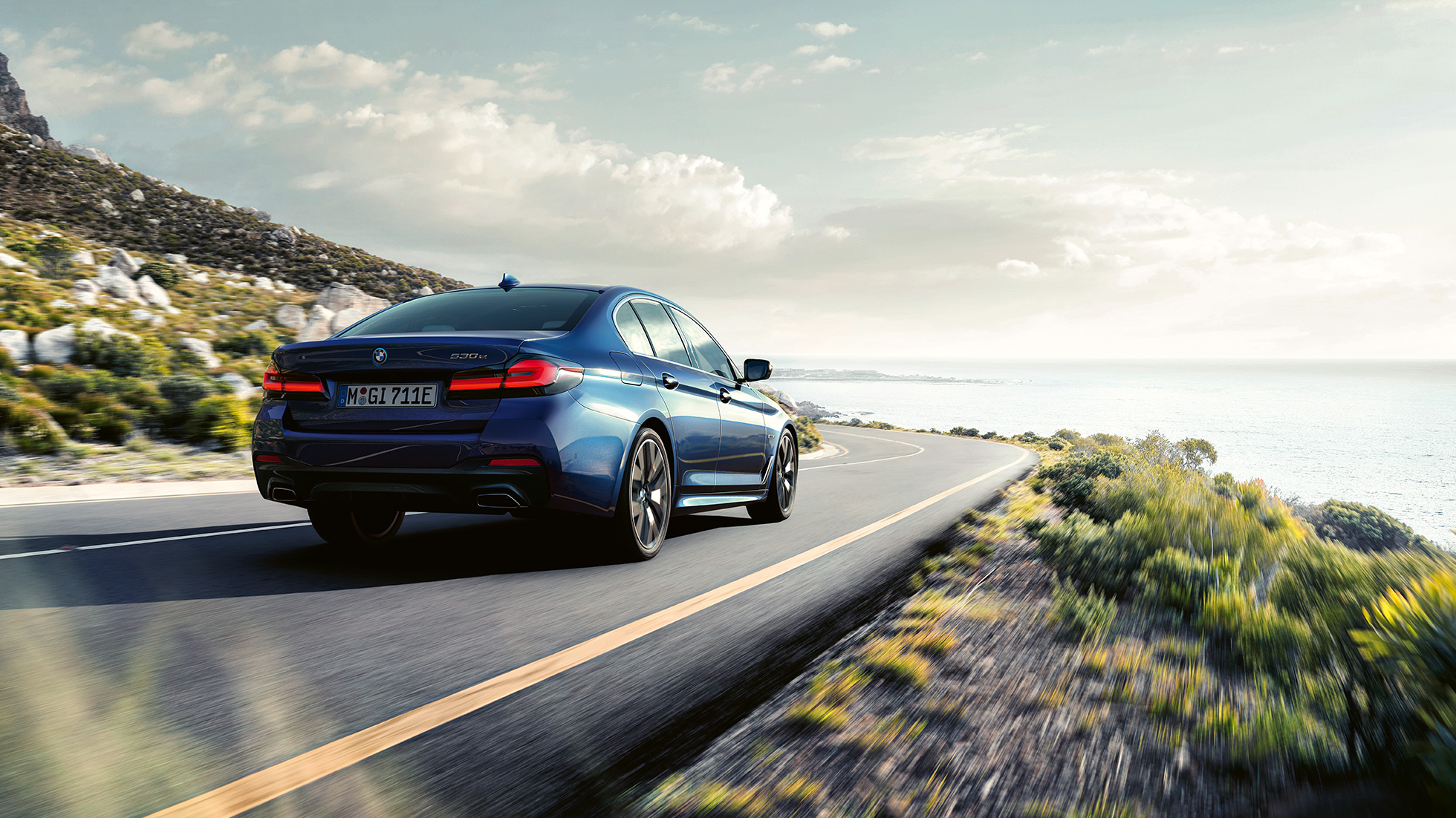 Driving dynamics BMW 5 Series Sedan G30 Driving dynamics BMW 5 Series Sedan G30 Phytonic Blue three-quarter rear view driving