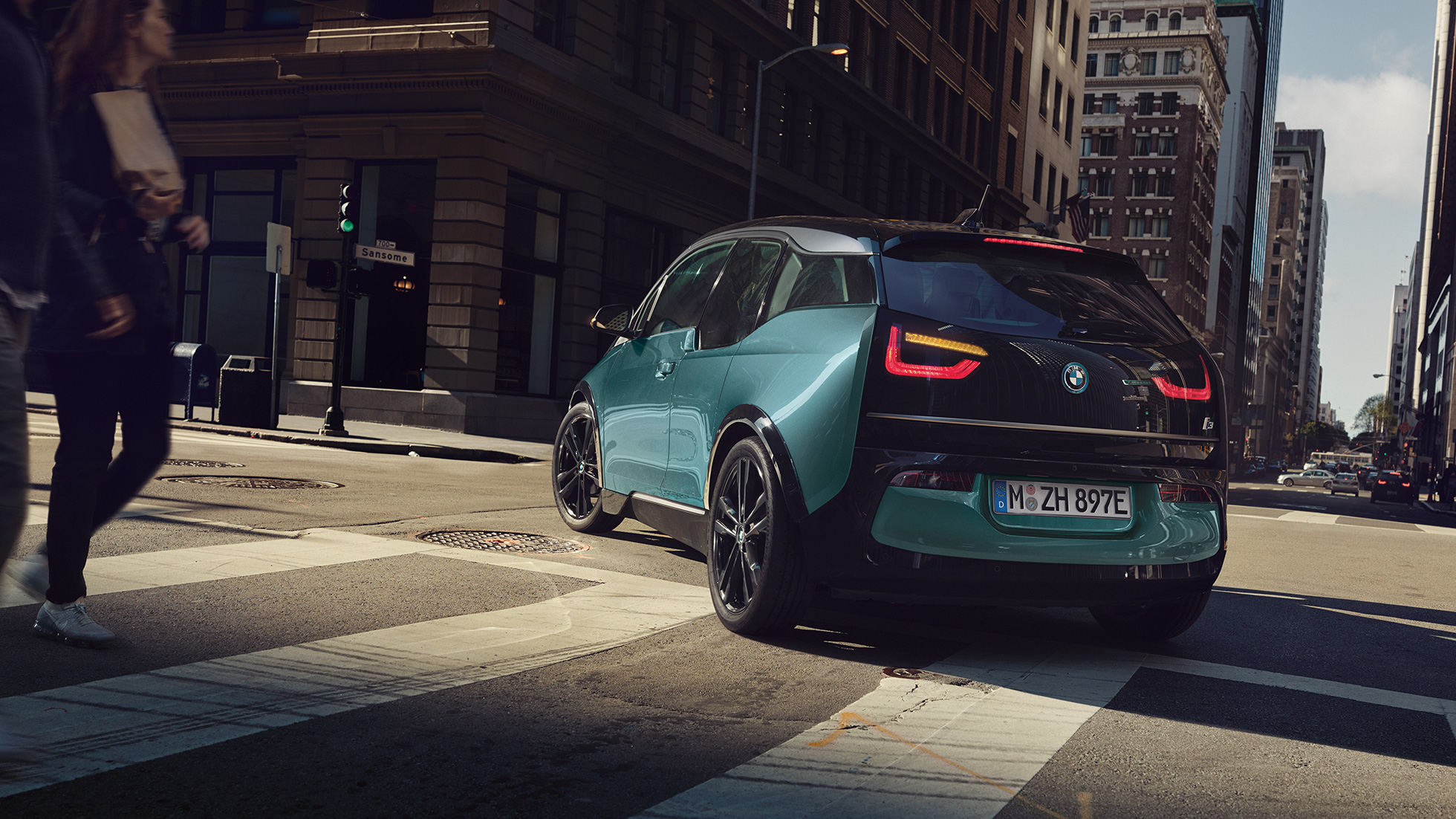 BMW i3 2018 three-quarter rear view driving BMW i3 I01 2018 Jucaro beige with Frozen Grey metallic highlight three-quarter rear view driving in urban setting